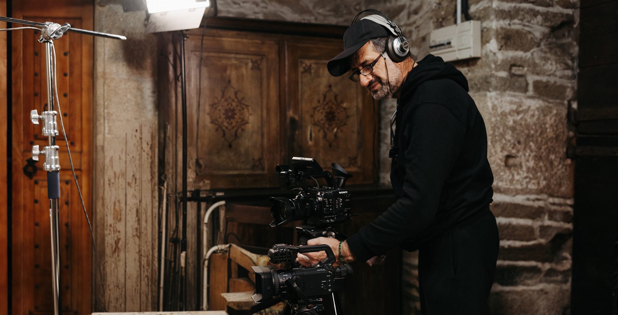 David Vázquez filming with a cinema camera and headphones in a stone house