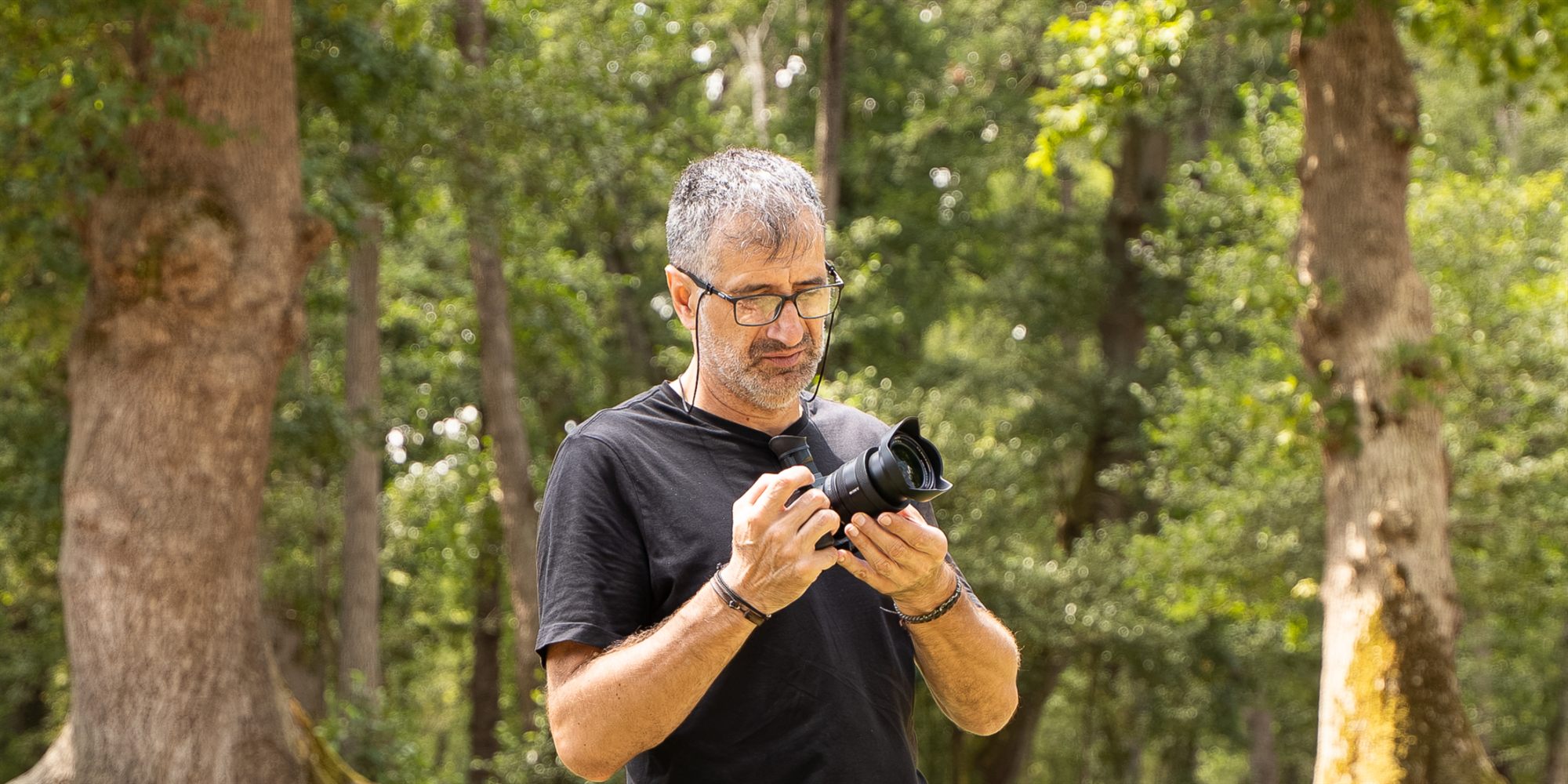 David Vázquez revisando su cámara en un bosque